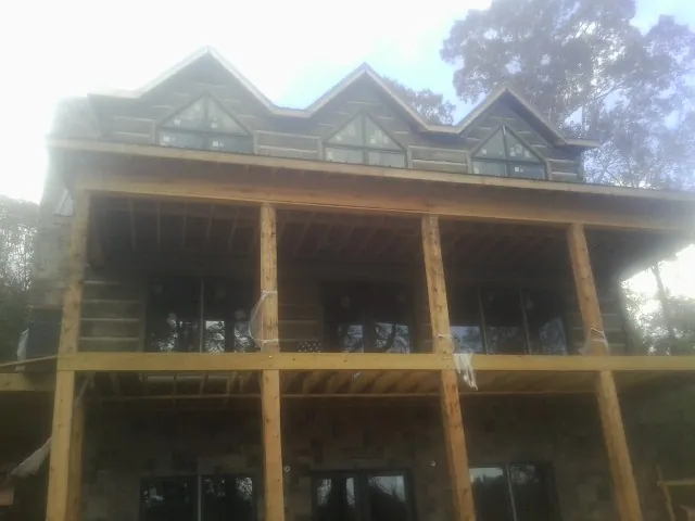 Dormers and porch framing on a large log home under construction — Roof Coating work by our crew in Glen Richey