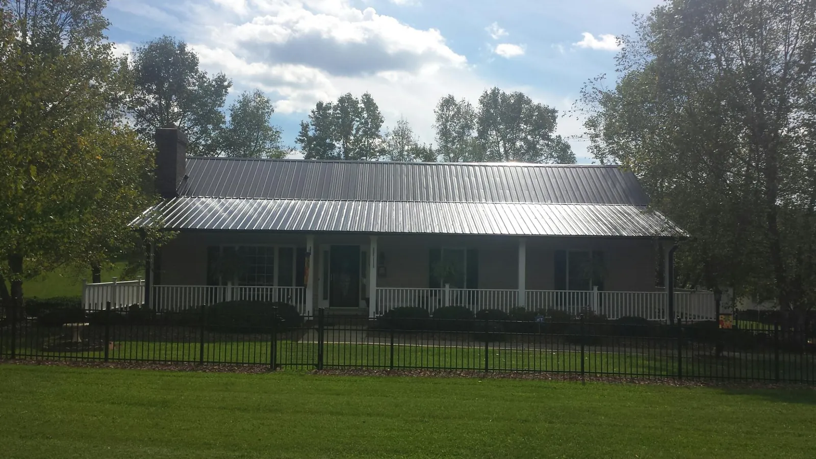 Gray metal roof on a brick ranch with a full width front porch — Gutter Guard Installation work by our crew in Glen Richey