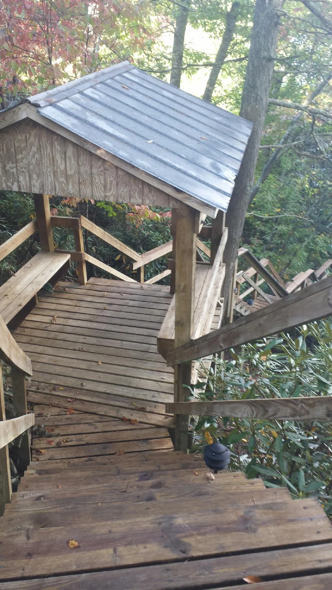 Metal roofed shelter over wooden steps on a wooded walkway — Skylight Repair & Installation work by our crew in Glen Richey