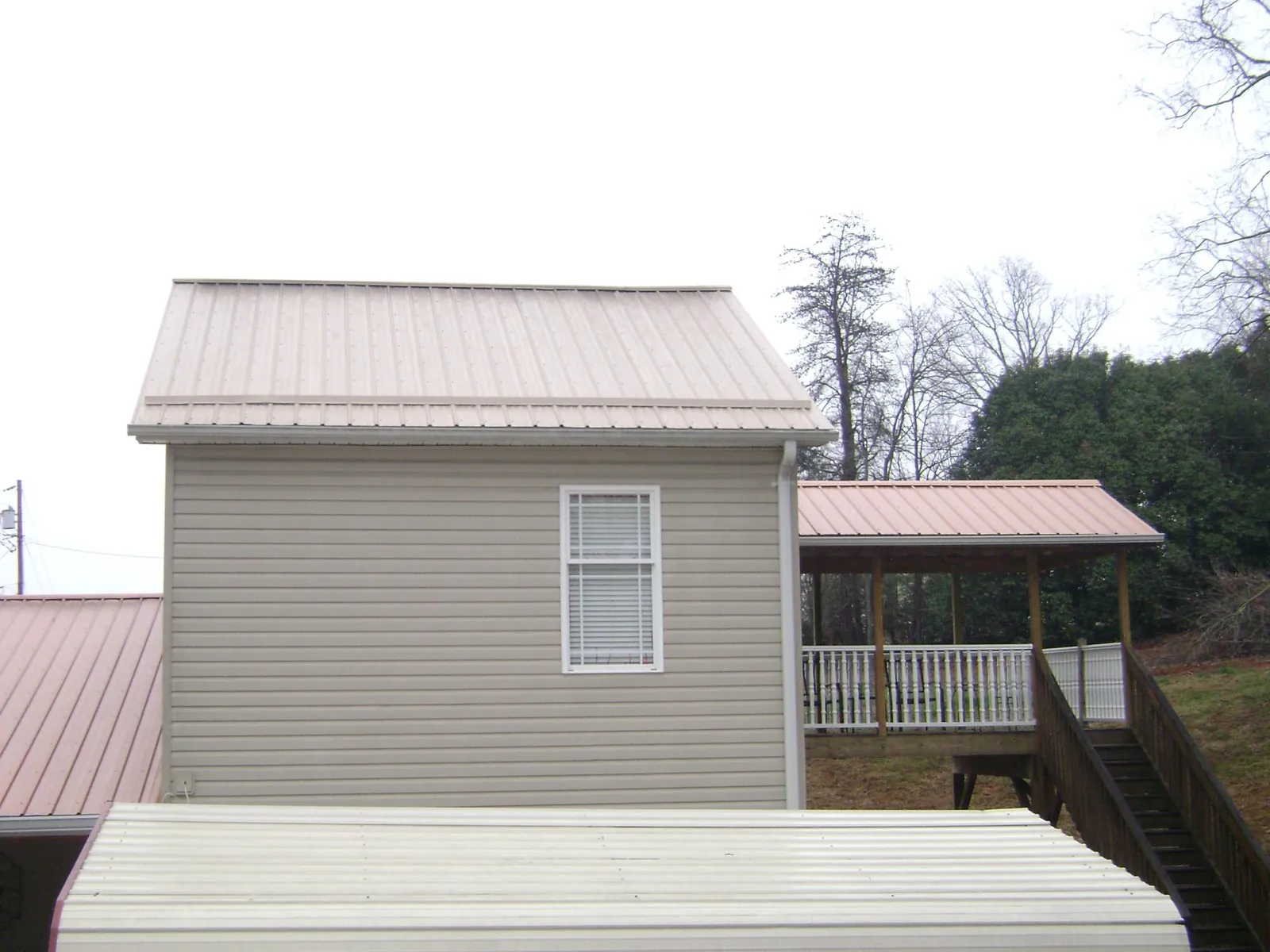 Tan metal roofs on a two story addition and attached porch, from a Roof Replacement job in Glen Richey