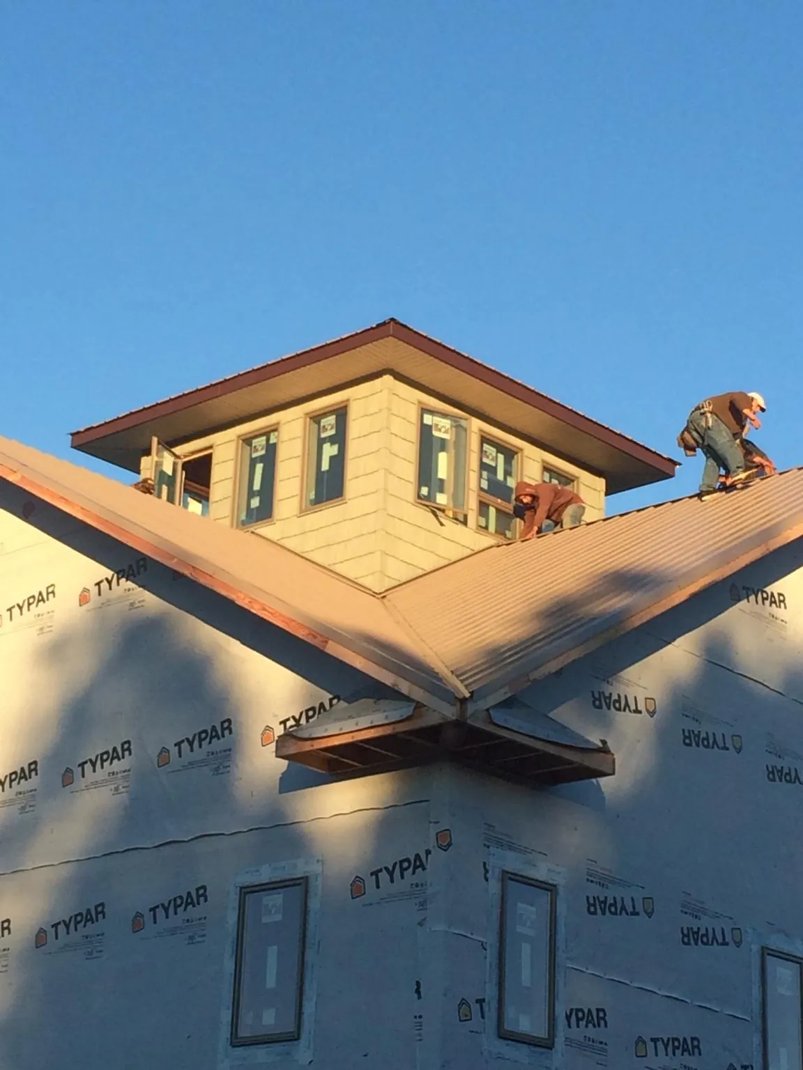 Roofers working around a rooftop cupola on a new metal roof at sunset — Roof Waterproofing in Glen Richey by Roofing Brothers
